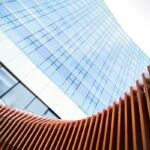 Low-angle view of a contemporary skyscraper facade with wooden architectural elements in the foreground.