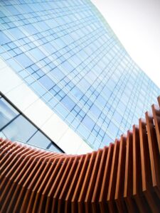 Low-angle view of a contemporary skyscraper facade with wooden architectural elements in the foreground.