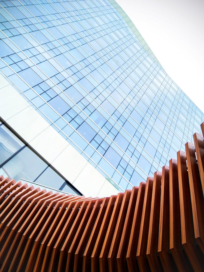 Low-angle view of a contemporary skyscraper facade with wooden architectural elements in the foreground.